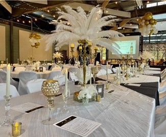 Elegant banquet hall with white feather centerpieces, gold decor, and set tables for an event