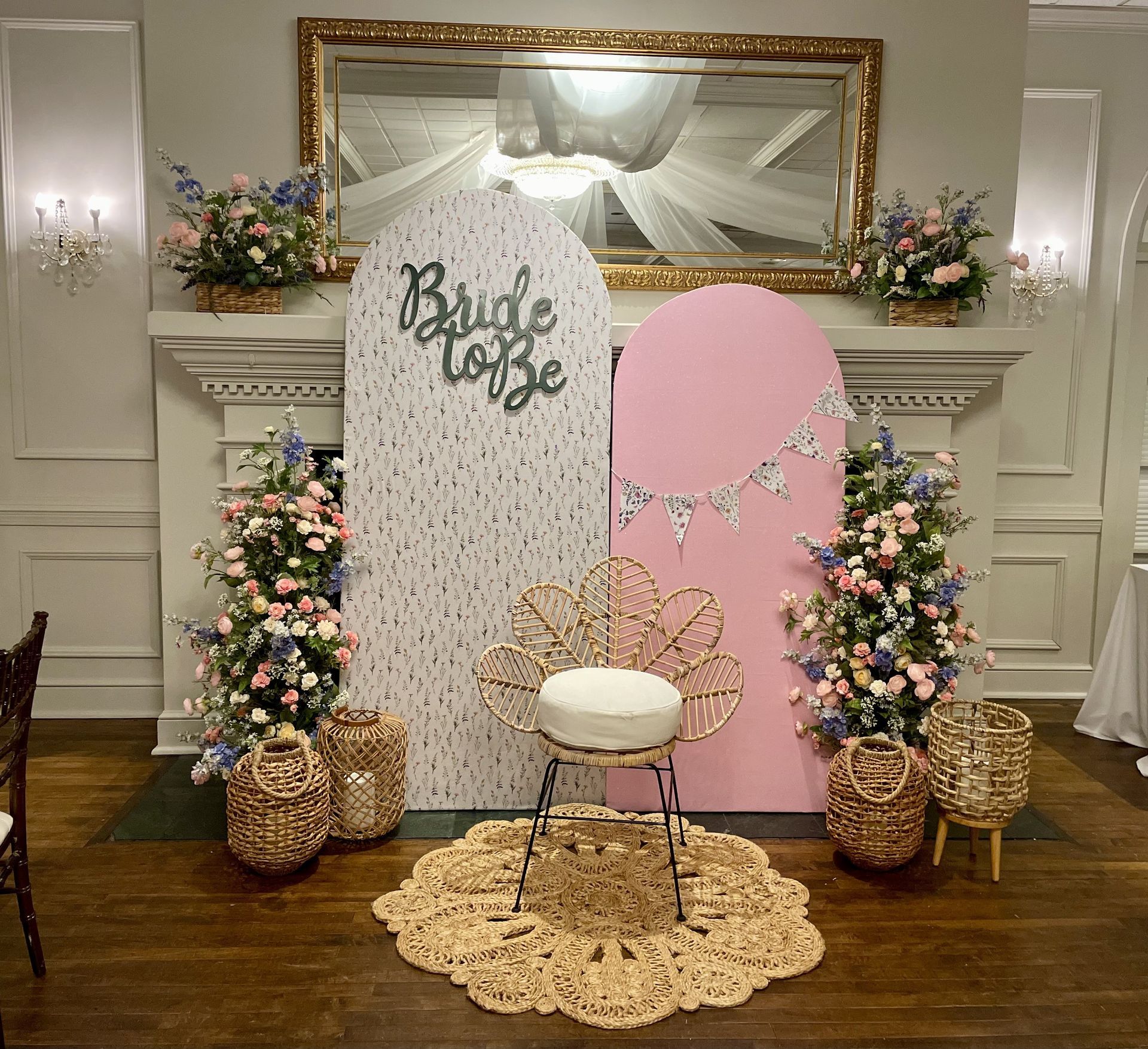 Pastel wedding welcome display with floral arrangements, gold chair, mirror, and “Bride to Be” sign