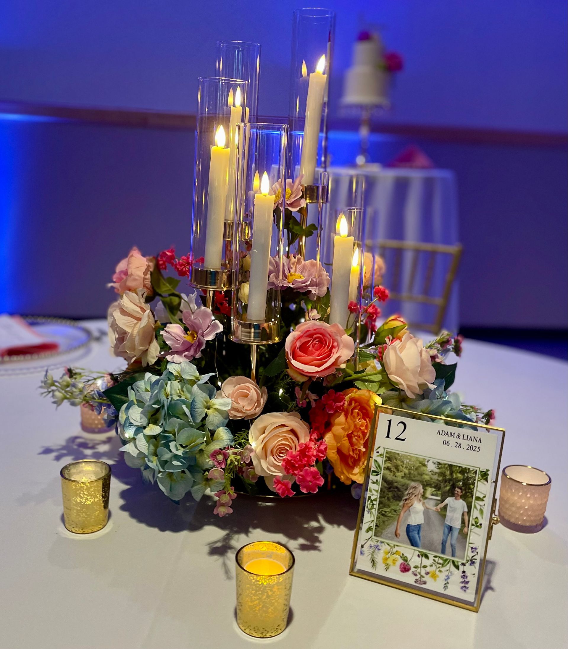 Elegant floral table centerpiece with candles and a small calendar on a white tablecloth at an event