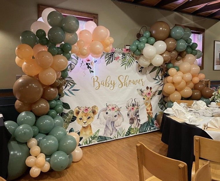 Baby shower backdrop with pastel balloon arch and puppy-themed sign in a decorated room