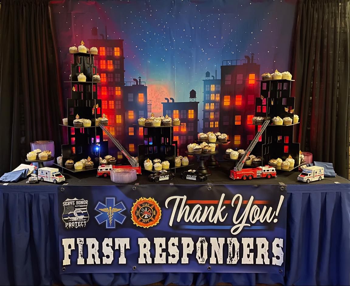 Thank You First Responders banner with memorial display of candles, flowers, and city skyline backdrop