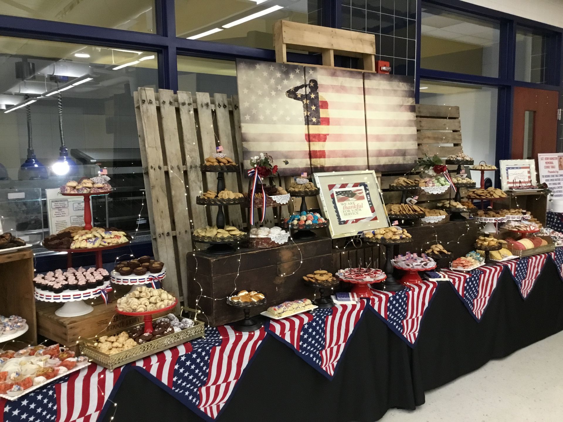 Buffet table with desserts and patriotic red, white, and blue bunting at an indoor event