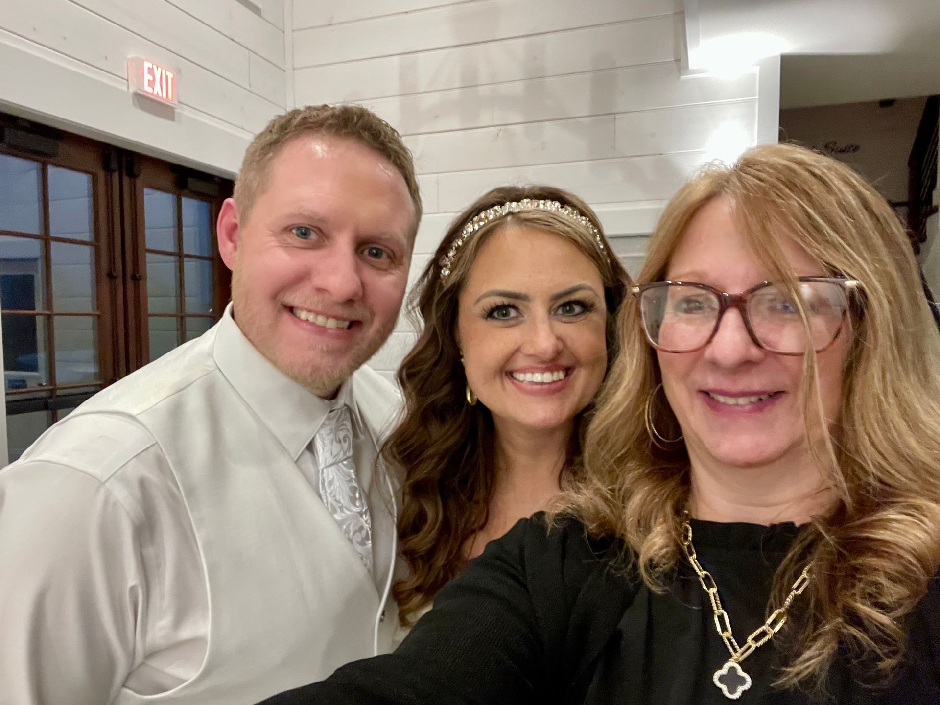 Three people smiling indoors at an event, posing for a selfie.