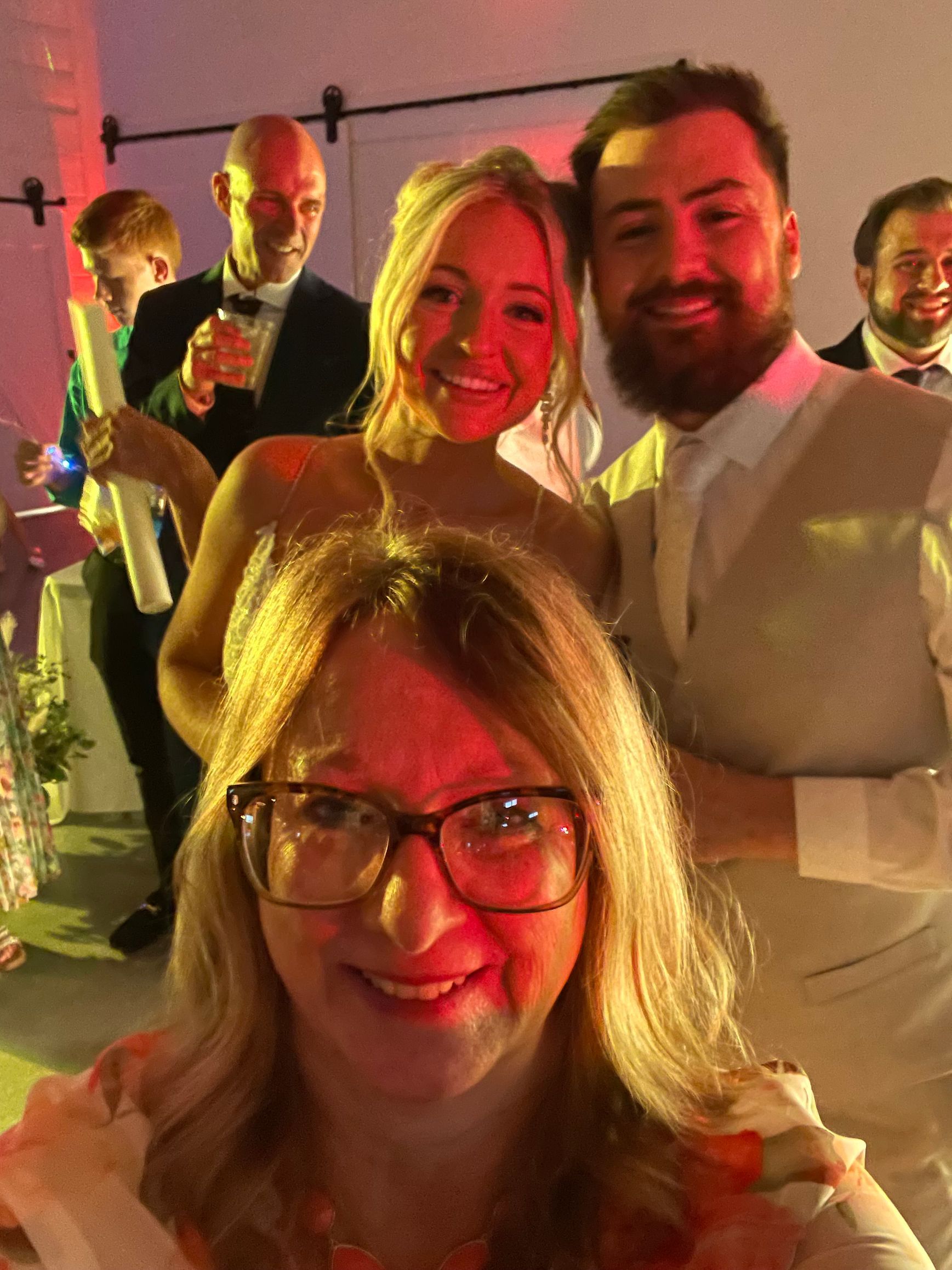 Four smiling people pose closely together at a warmly lit indoor event.