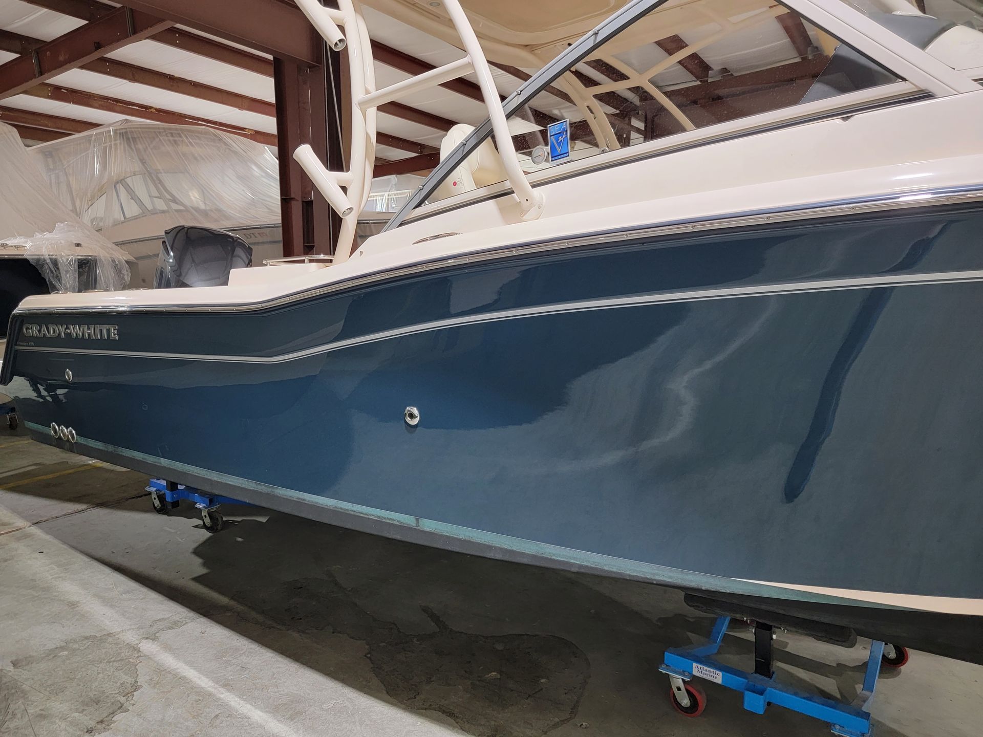 A blue and white boat is parked in a warehouse.