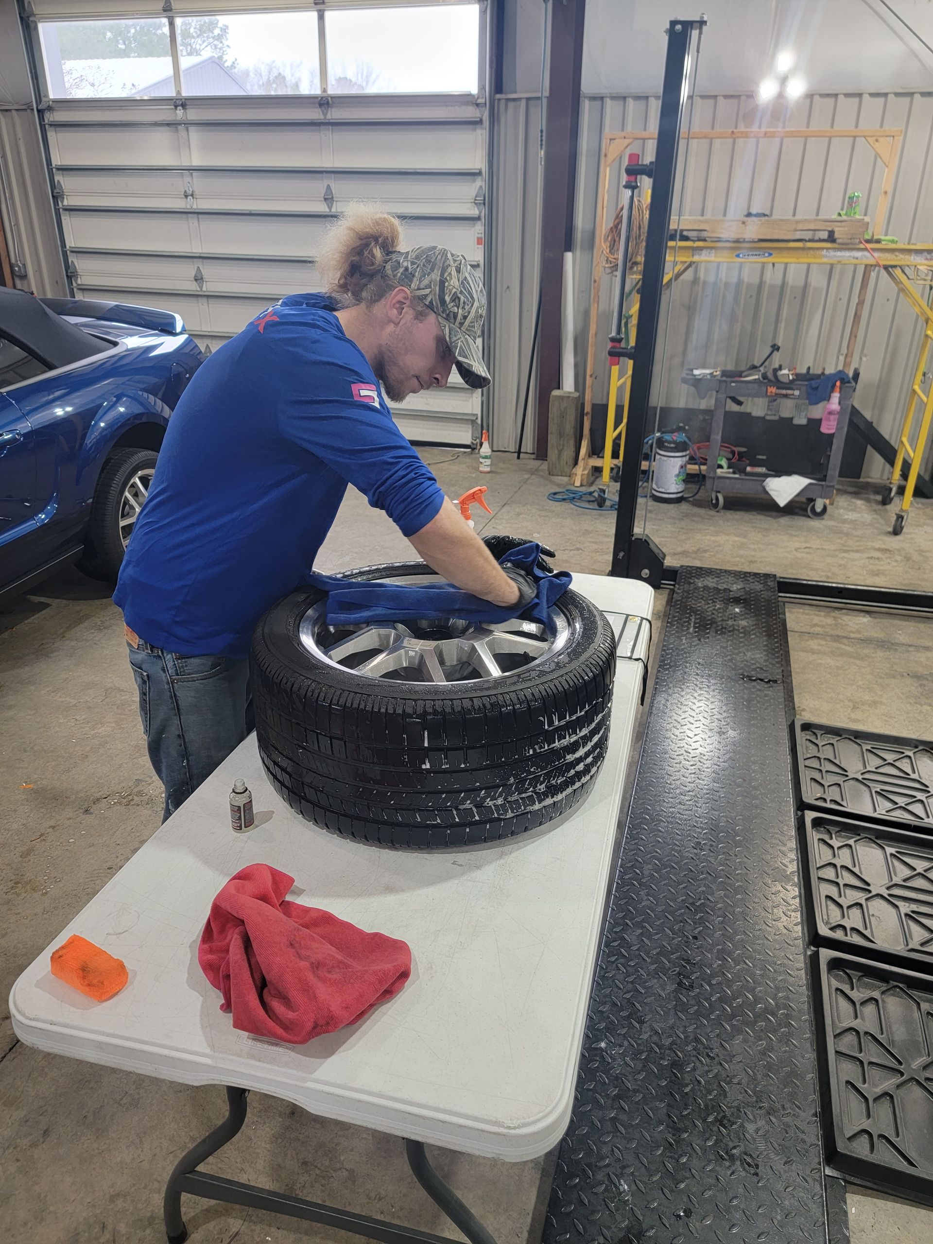 A man is cleaning a tire on a table in a garage.