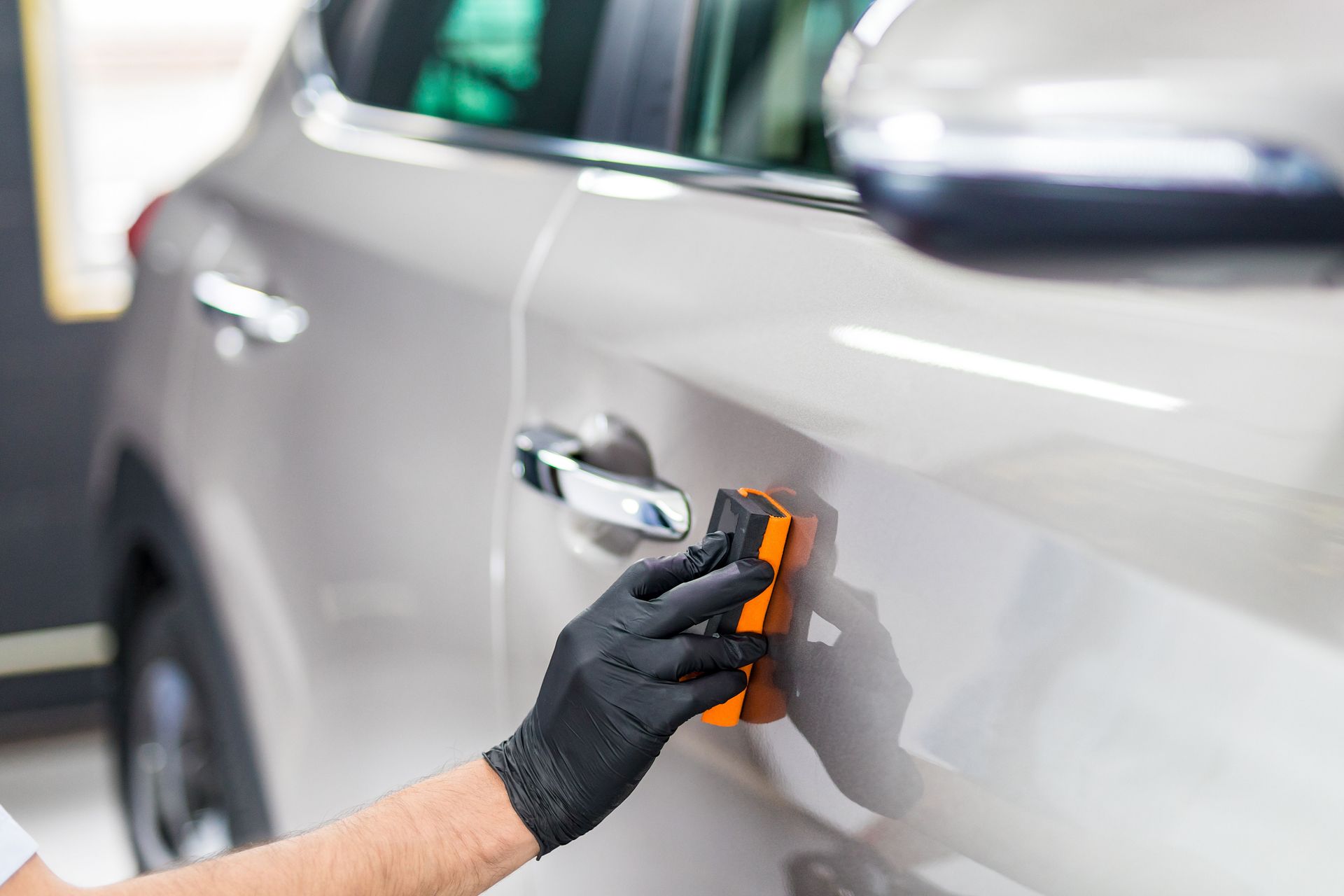 A person is polishing a car with a sponge.