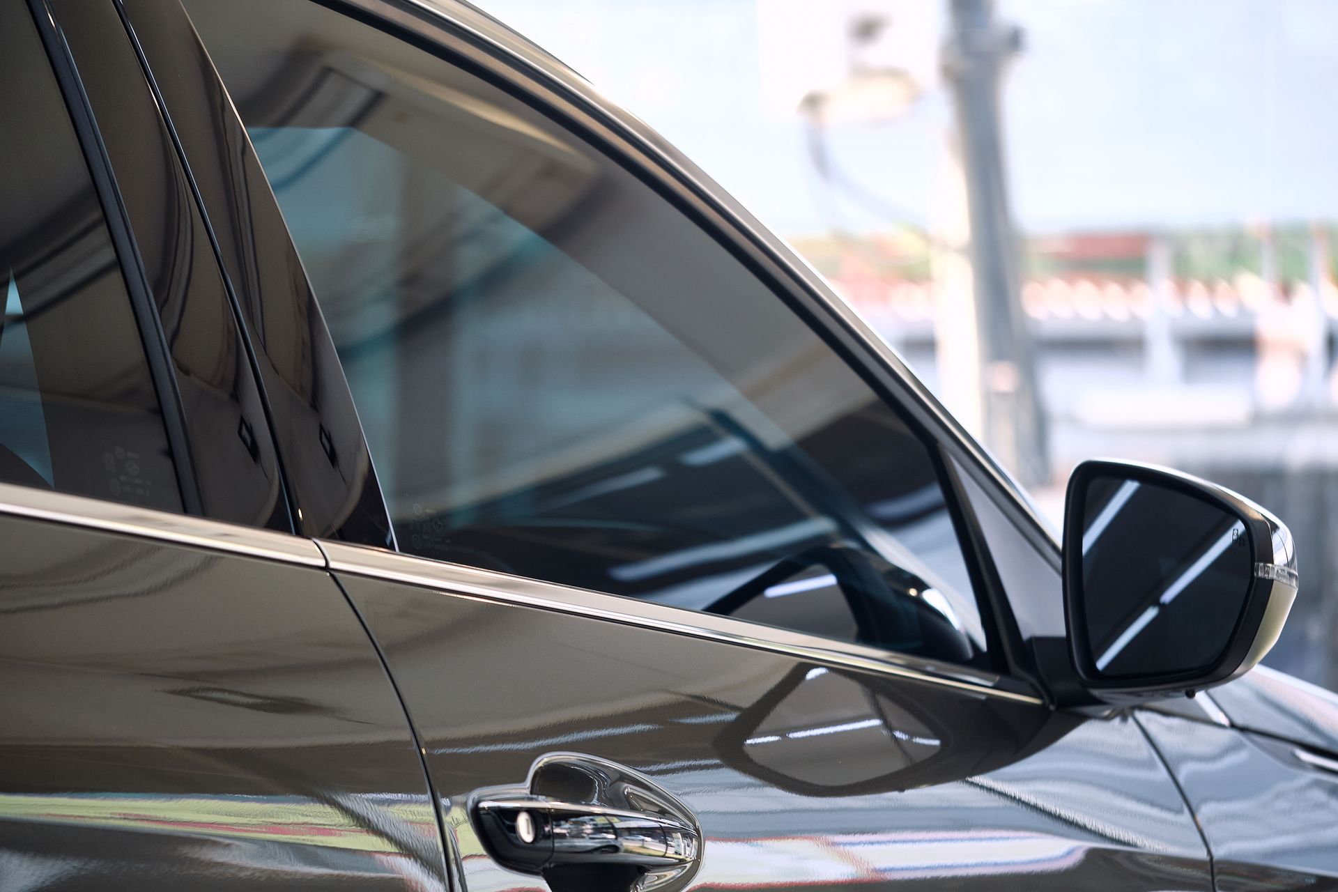 A black car is parked in a parking lot with the door open.