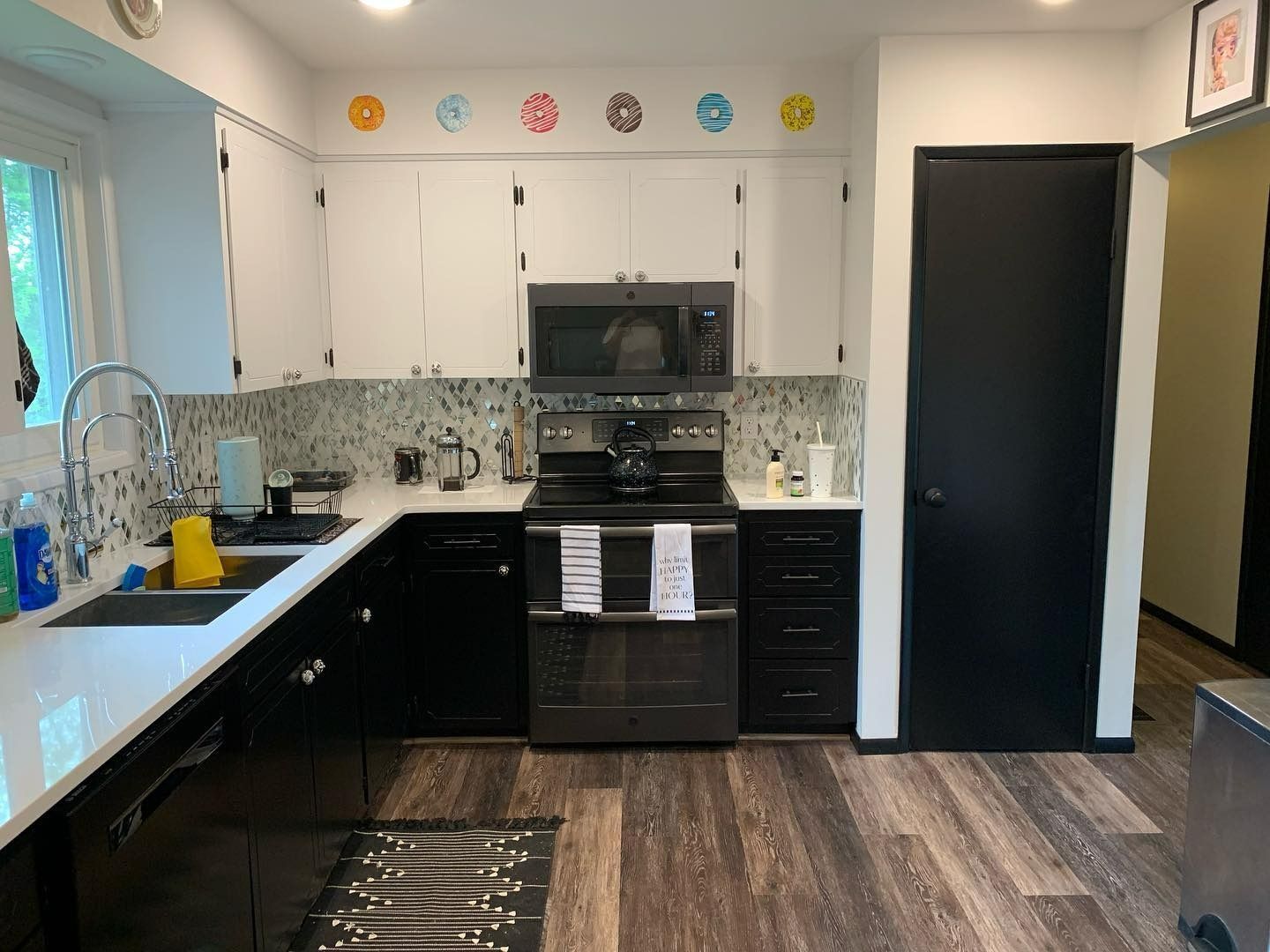 Kitchen with black and white cabinets, stainless steel appliances, and a mosaic tile backsplash.