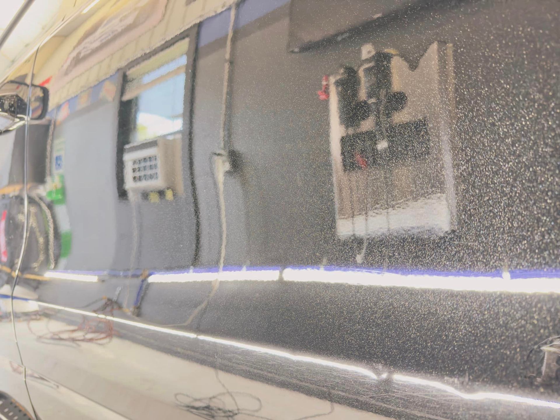 Black vehicle side, reflective surface, with equipment mounted on the side wall.