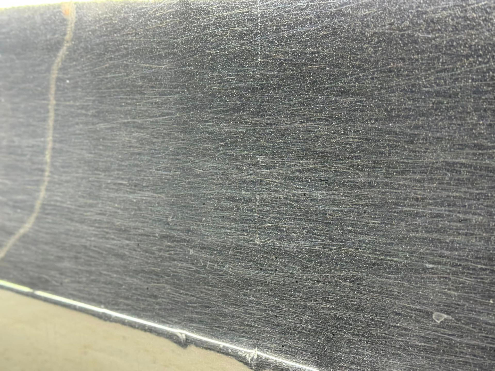 Close-up of a dark, textured surface with horizontal striations and light-colored streaks.