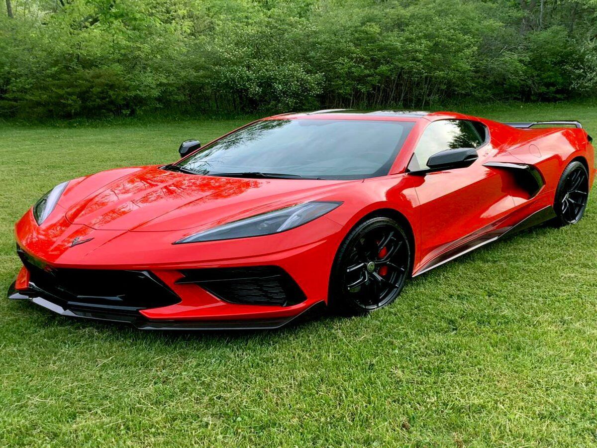 Red Chevrolet Corvette sports car parked on green grass.