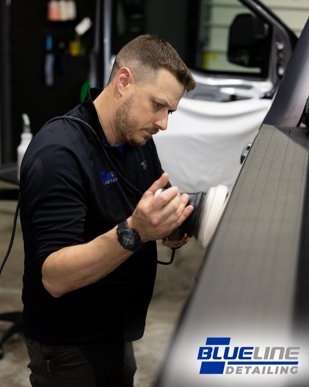 Man polishing a car panel with a buffer tool, inside a garage, with 