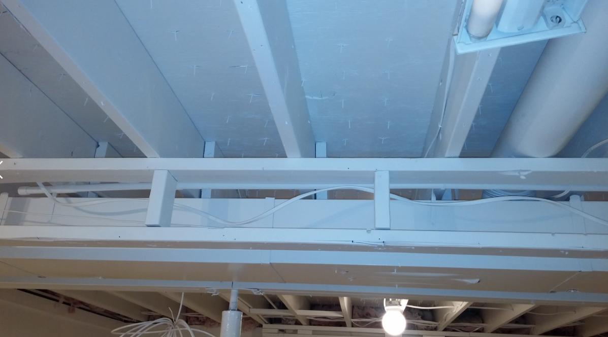 Empty basement with white walls, blue ceiling beams, and concrete floor.
