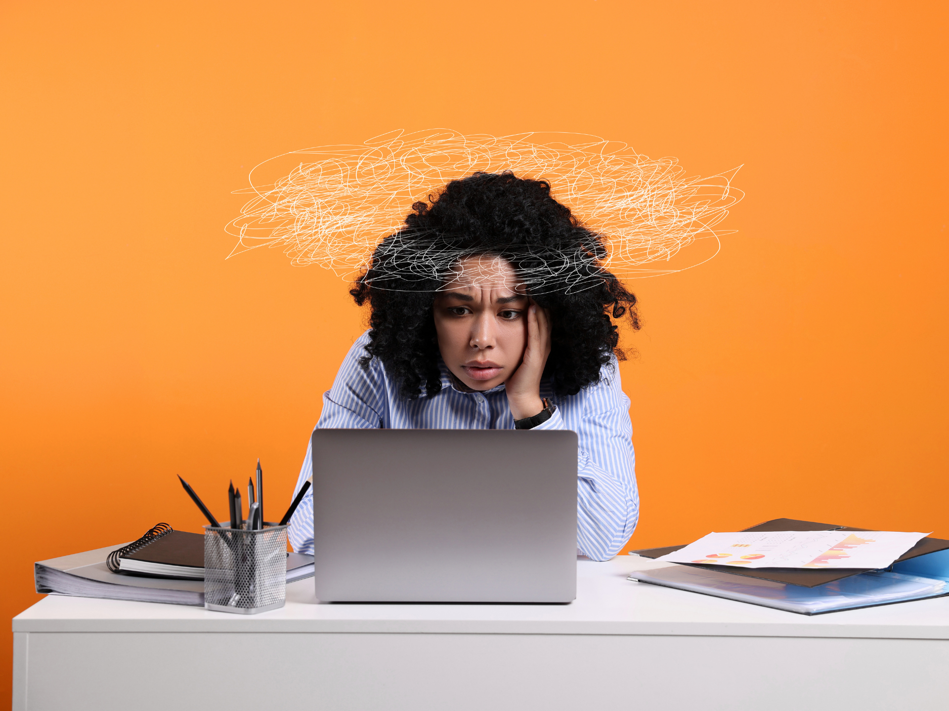 Person stressed at a desk with a laptop, papers, and orange background