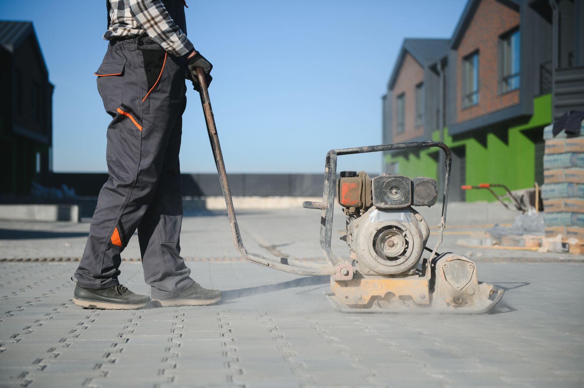 A man is using a machine to compact concrete on a construction site.