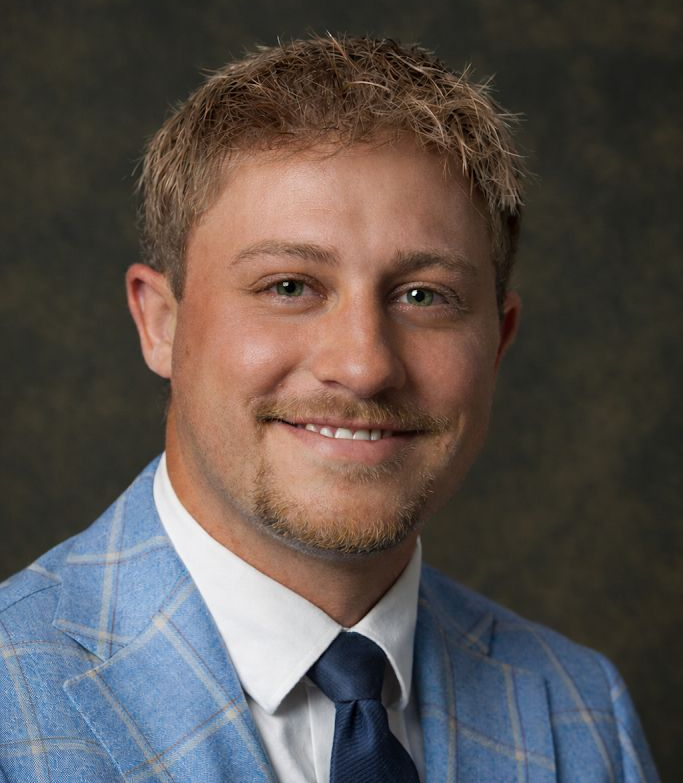 A young man in a suit and tie is smiling for the camera.