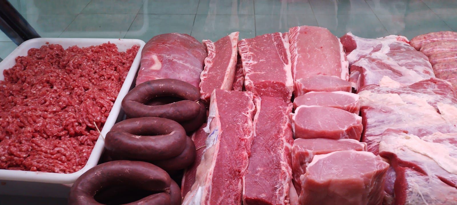 Vitrina con variedad de carnes crudas: carne picada, morcilla, chuletas de cerdo y otros cortes.