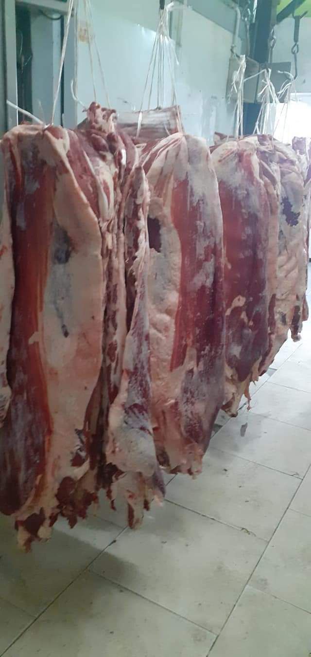 Canales colgando en una carnicería, carne roja y blanca, iluminación cenital, suelo de baldosas.