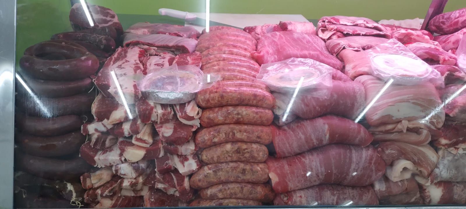 Exhibición de diversas carnes crudas: morcilla, salchichas, cortes envueltos en tocino y cortes de carne.