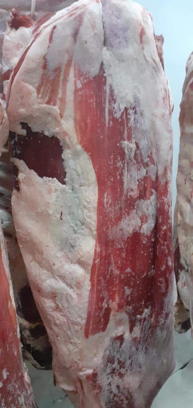 Primer plano de un gran corte de carne cruda, probablemente de res, con músculo rojo visible y grasa blanca.