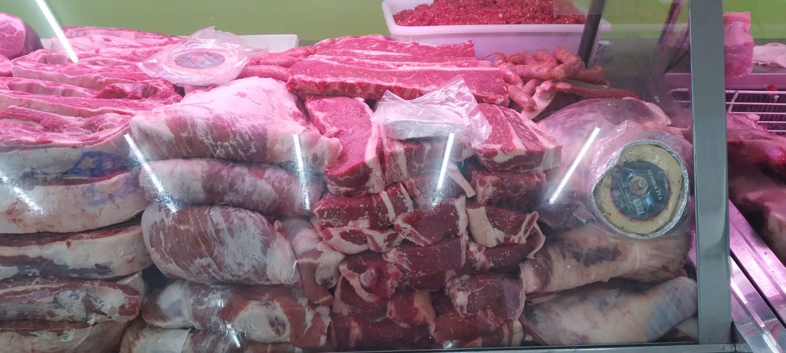 Exhibición de diferentes cortes de carne cruda en el refrigerador de una carnicería.