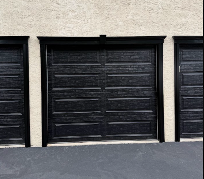 Three black garage doors in a beige stucco building facade.
