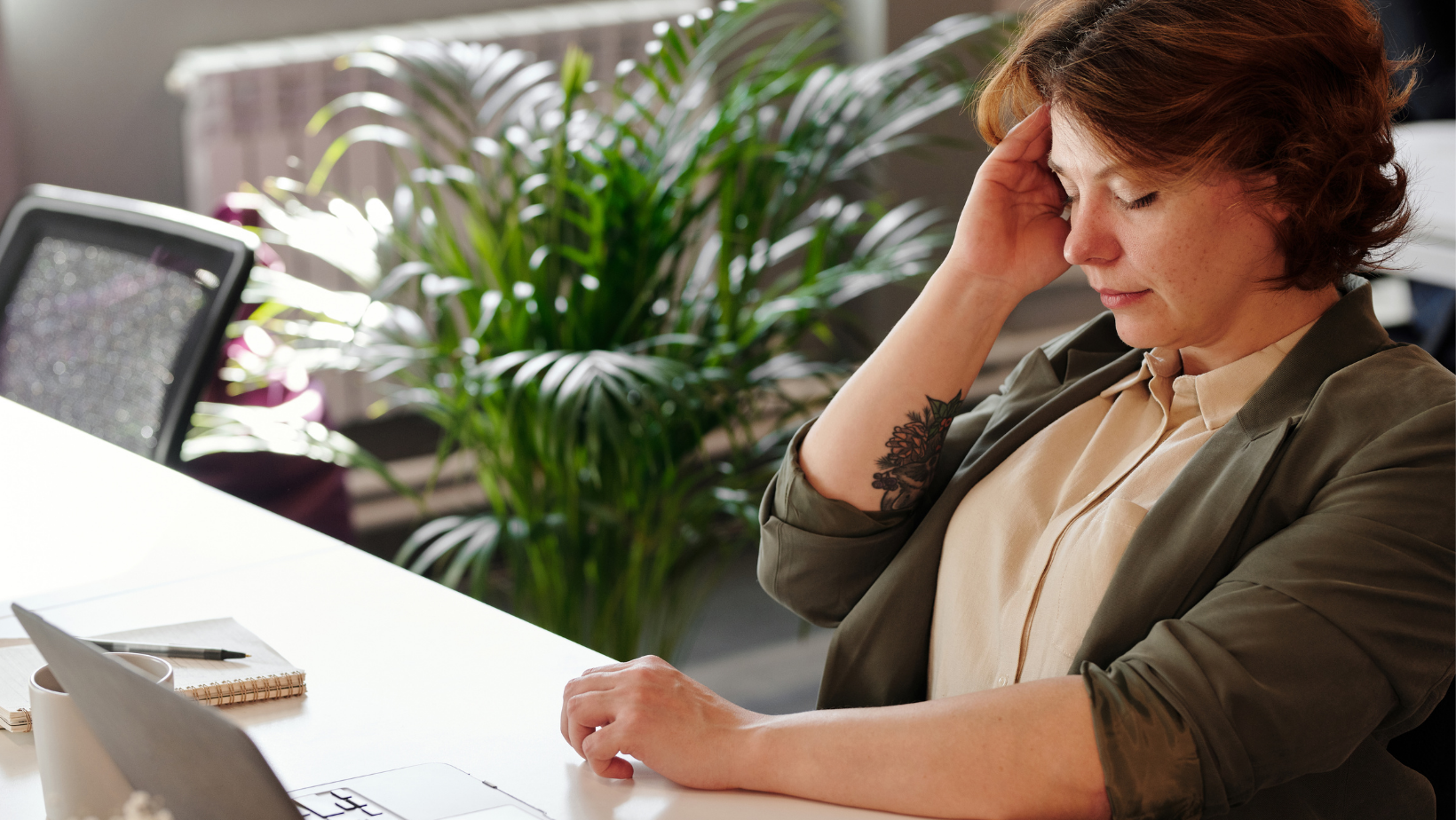 A woman is sitting at a desk using a laptop computer.