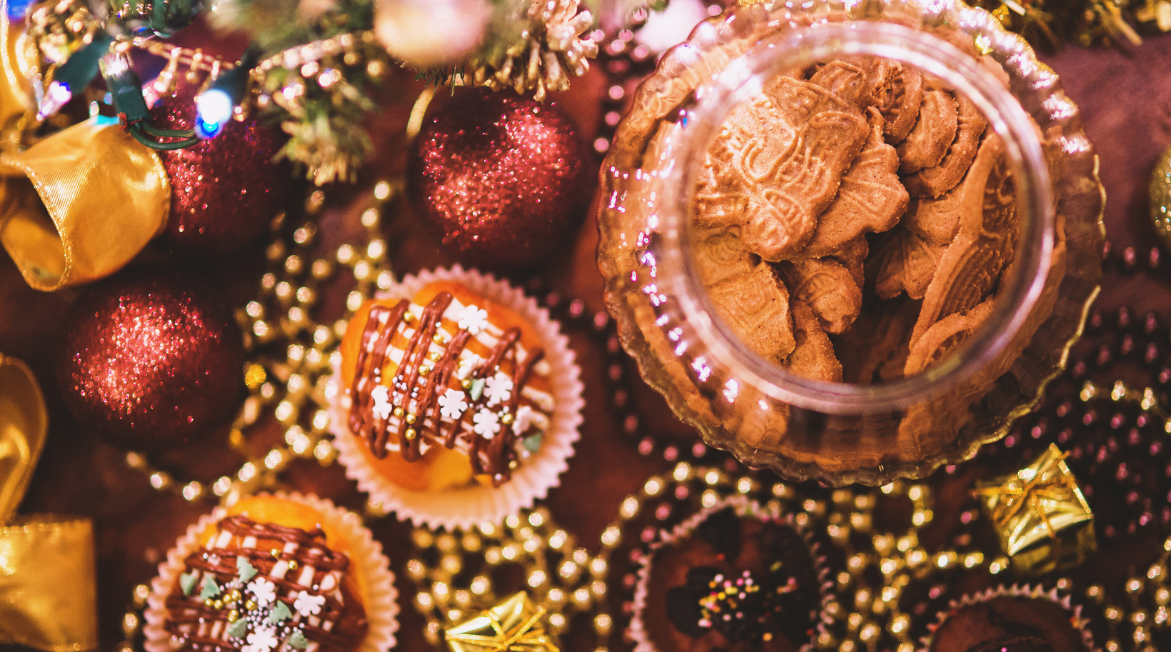 A table topped with cupcakes , cookies , and christmas decorations.