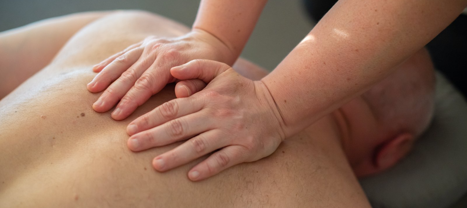 A person is giving a man a massage on his back.