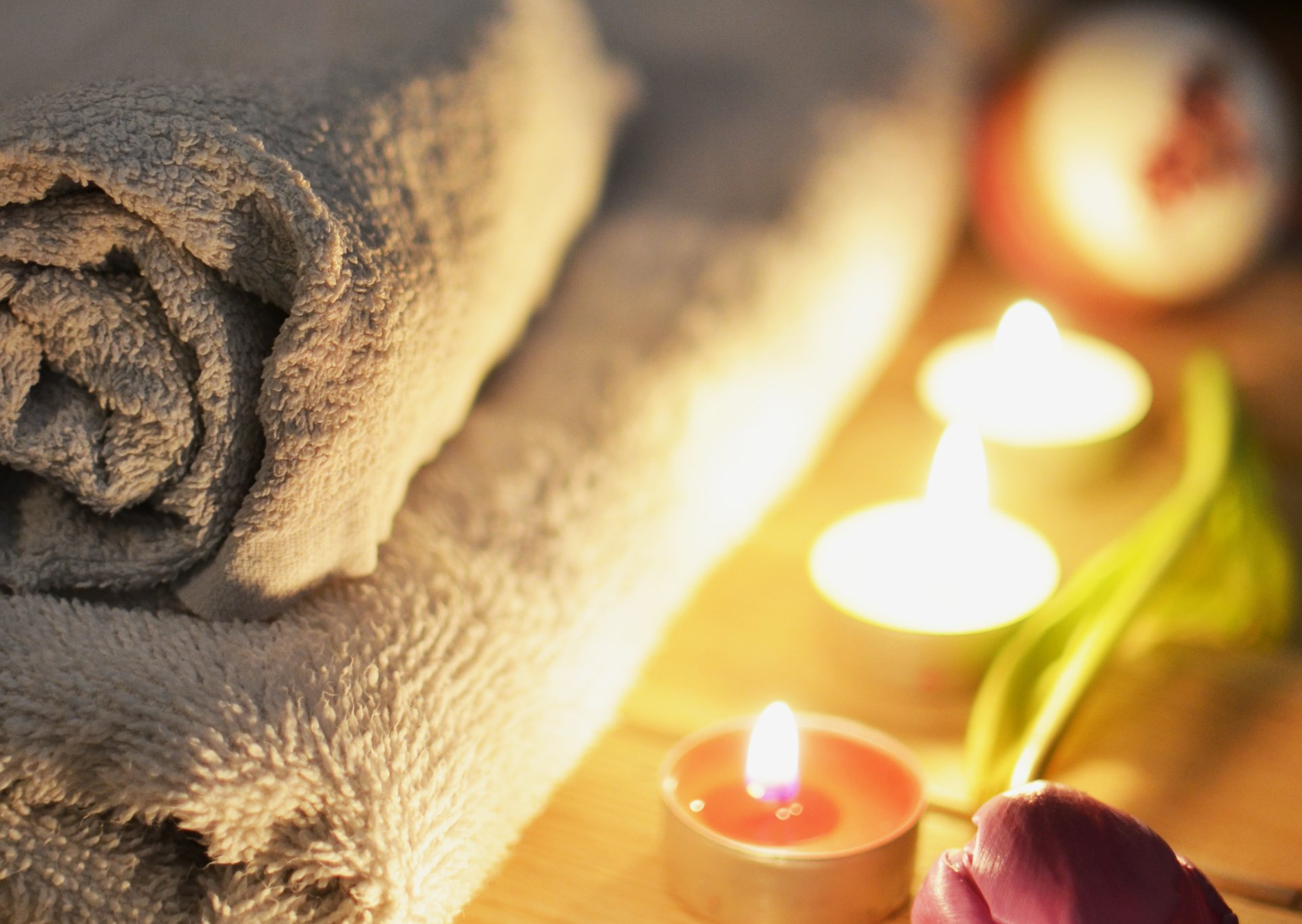 A stack of towels and candles on a wooden table.