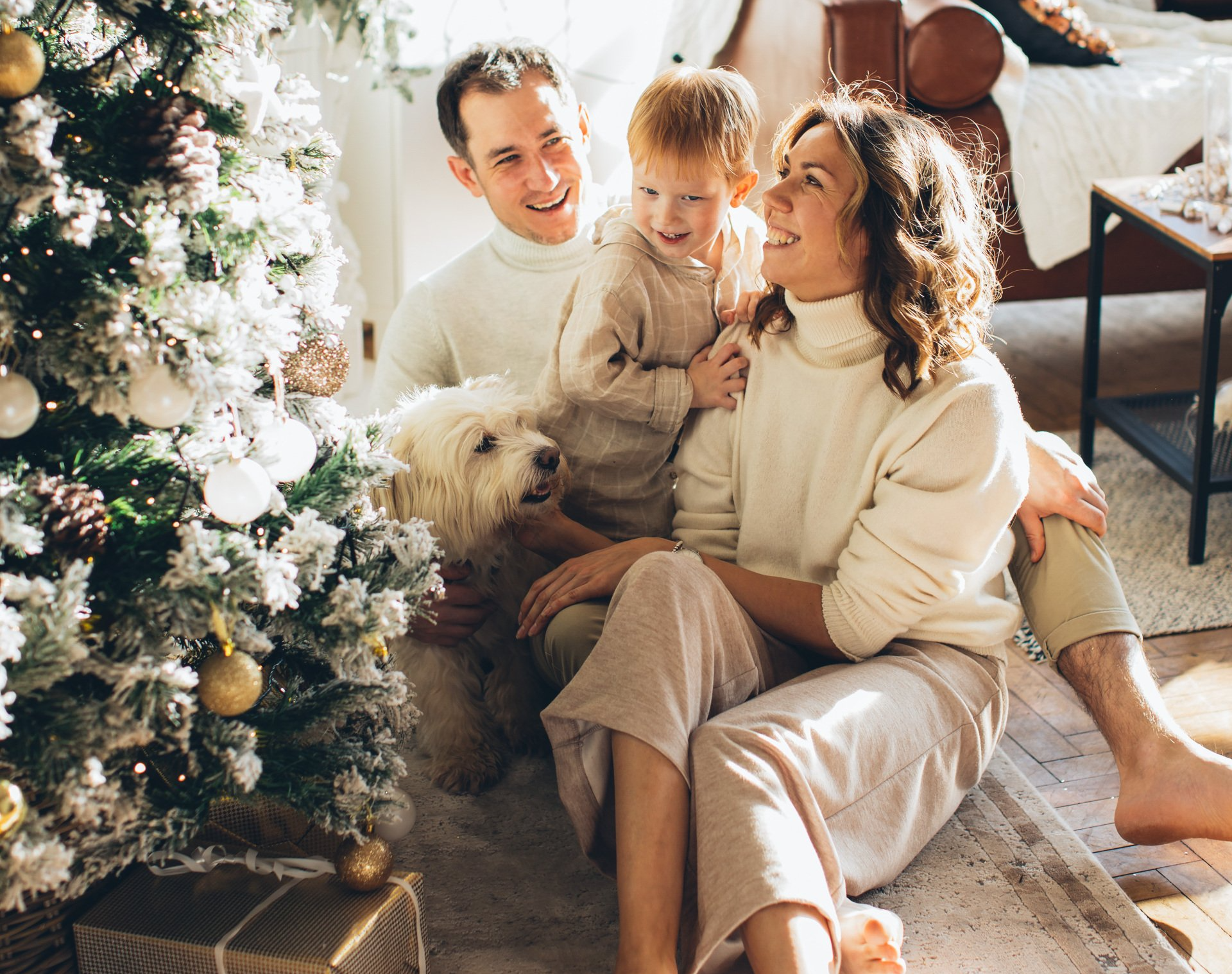 A family is sitting on the floor in front of a christmas tree.