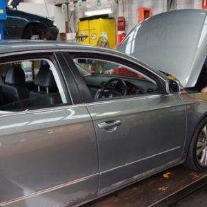 Man is Working on a Car in a Garage With the Hood Open — Oaks Automotive Pty Ltd in Oak Flats, NSW