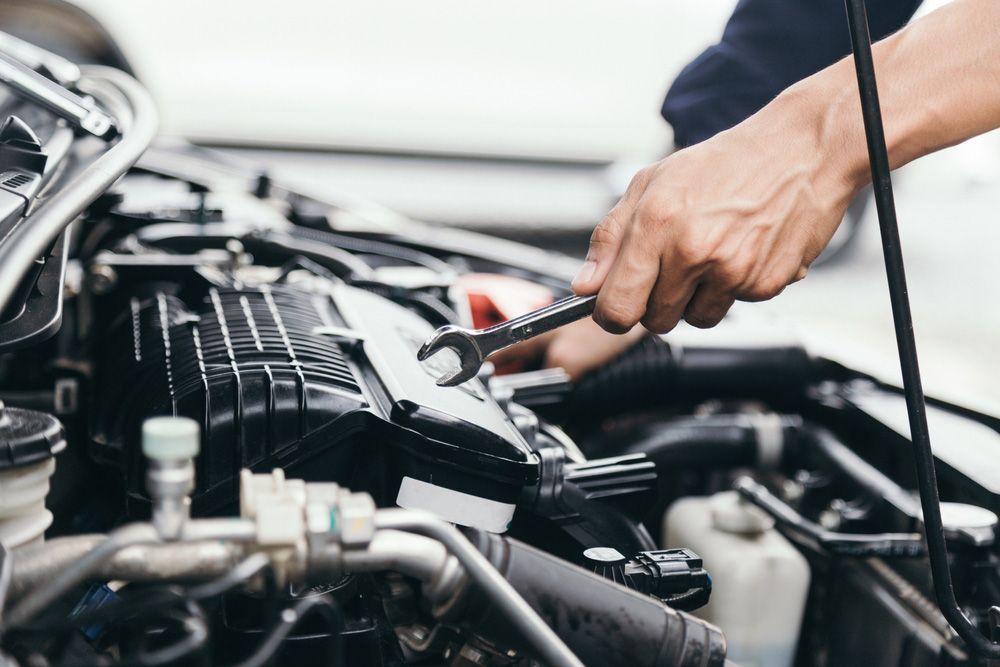 Man is Working on the Engine of a Car With a Wrench — Oaks Automotive Pty Ltd in Oak Flats, NSW