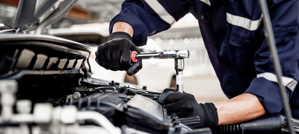 Man is Working on a Car Engine With a Wrench — Oaks Automotive Pty Ltd in Oak Flats, NSW