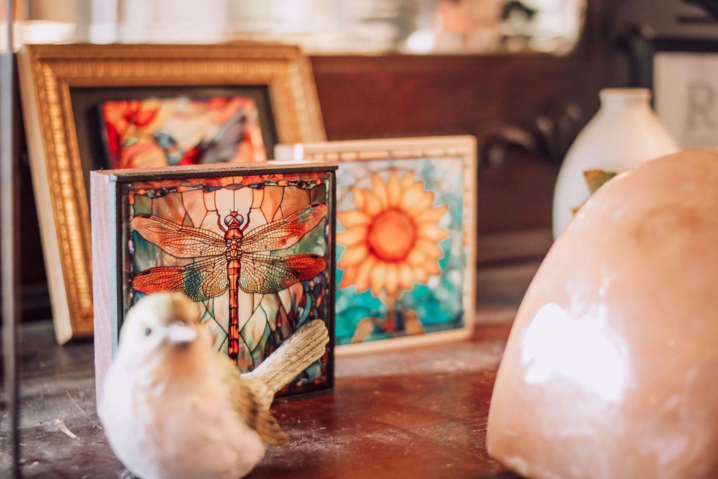 Ceramic bird and floral art blocks on a wooden surface, with a gilded picture frame and decorative vase.