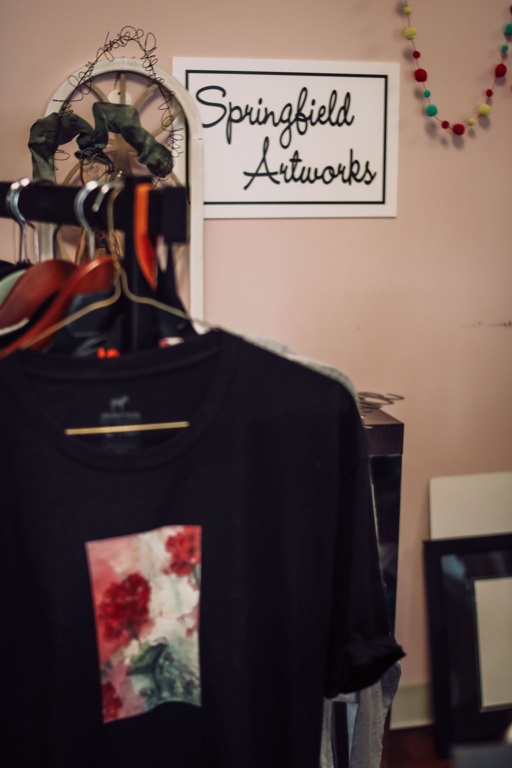 Black t-shirt with floral design hangs in front of a 
