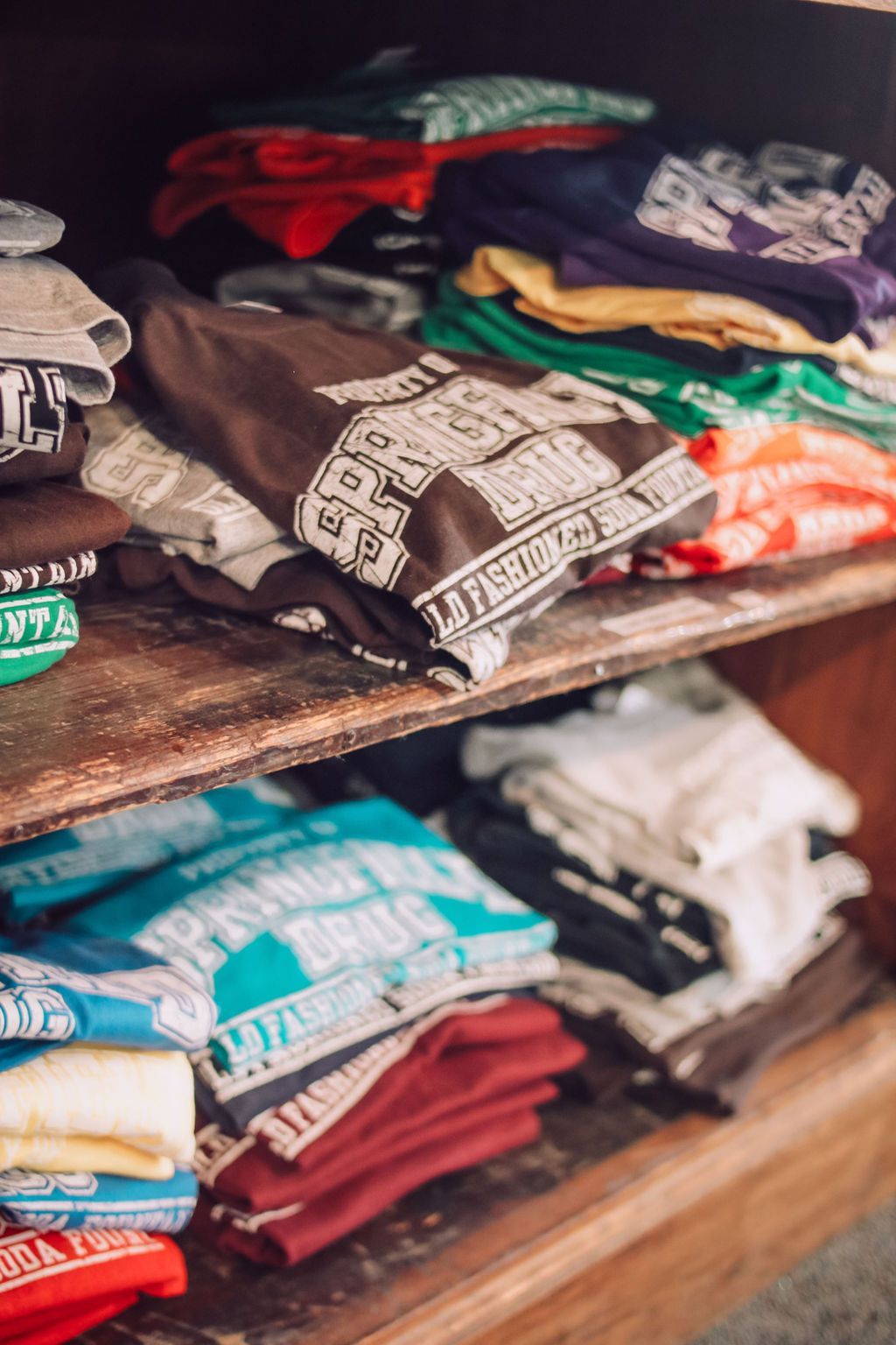 Shelves stacked with neatly folded colorful t-shirts, various designs visible.