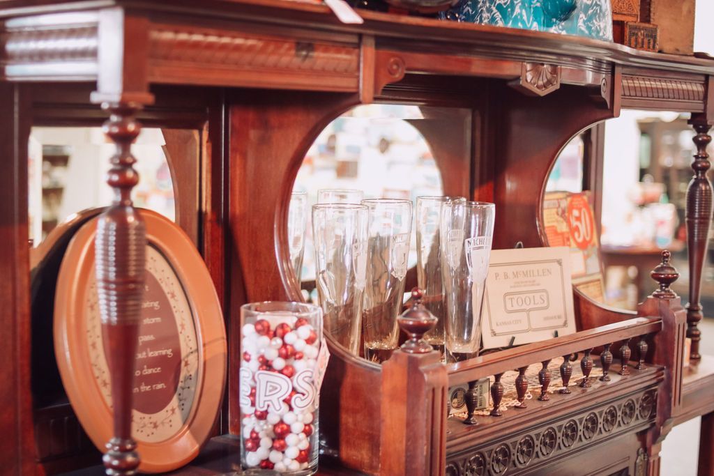 Wooden antique shelf with glassware and a framed oval picture.