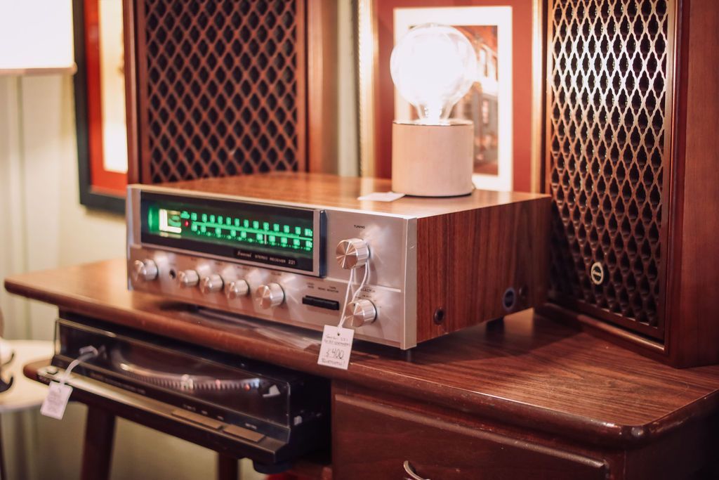 Vintage stereo receiver with wood paneling, speakers, and a lamp on a wooden table.