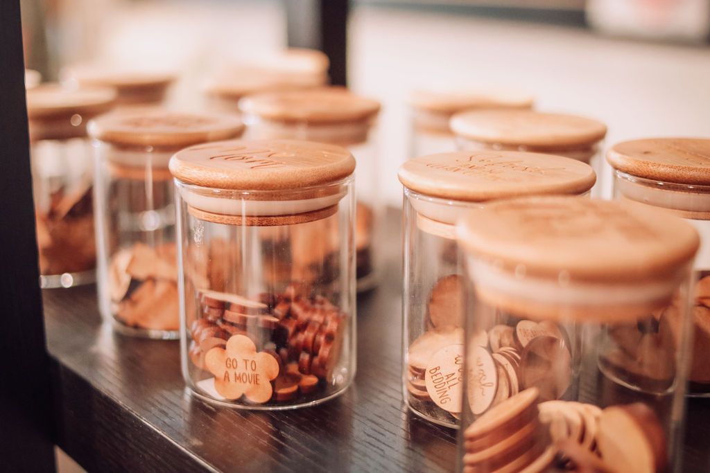 Glass jars with wooden lids and contents, on a dark shelf.