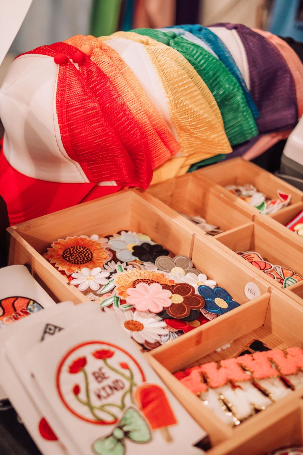 Rainbow-colored headbands and floral accessories displayed in wooden trays at a shop. 