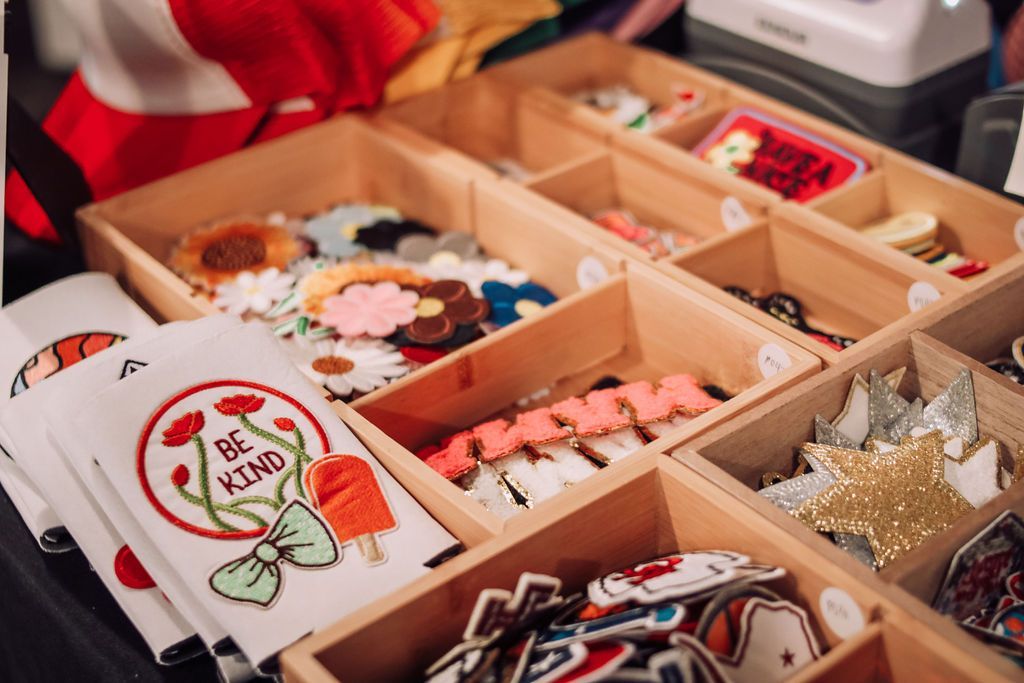 Wooden display case filled with colorful enamel pins and patches; 