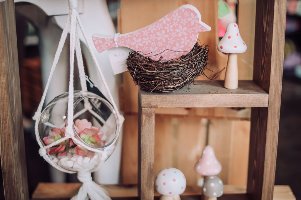 Wooden shelf with pink bird decor, macrame planter, and mushroom figurines.