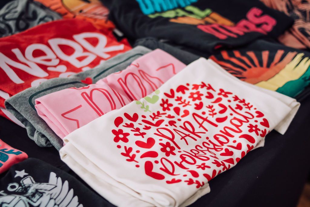Pile of colorful textiles with graphic designs. Includes heart, text, and sunburst motifs.