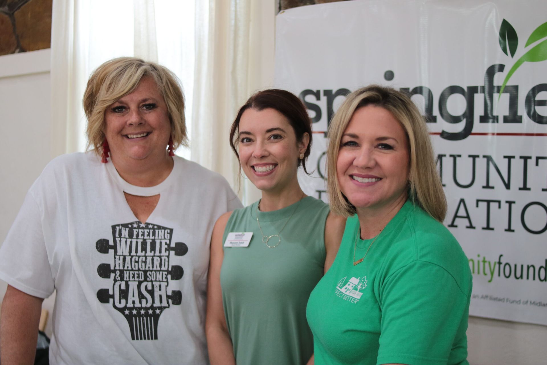 Three women smiling at the camera near a 