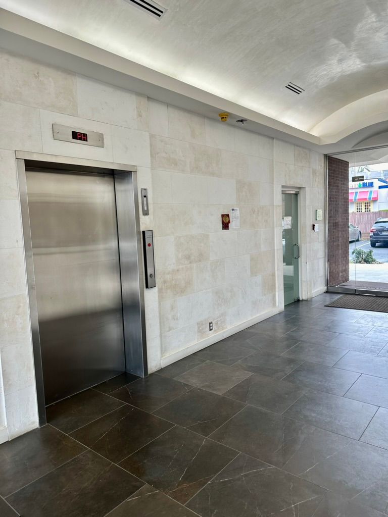A stainless steel elevator is in the middle of a building.