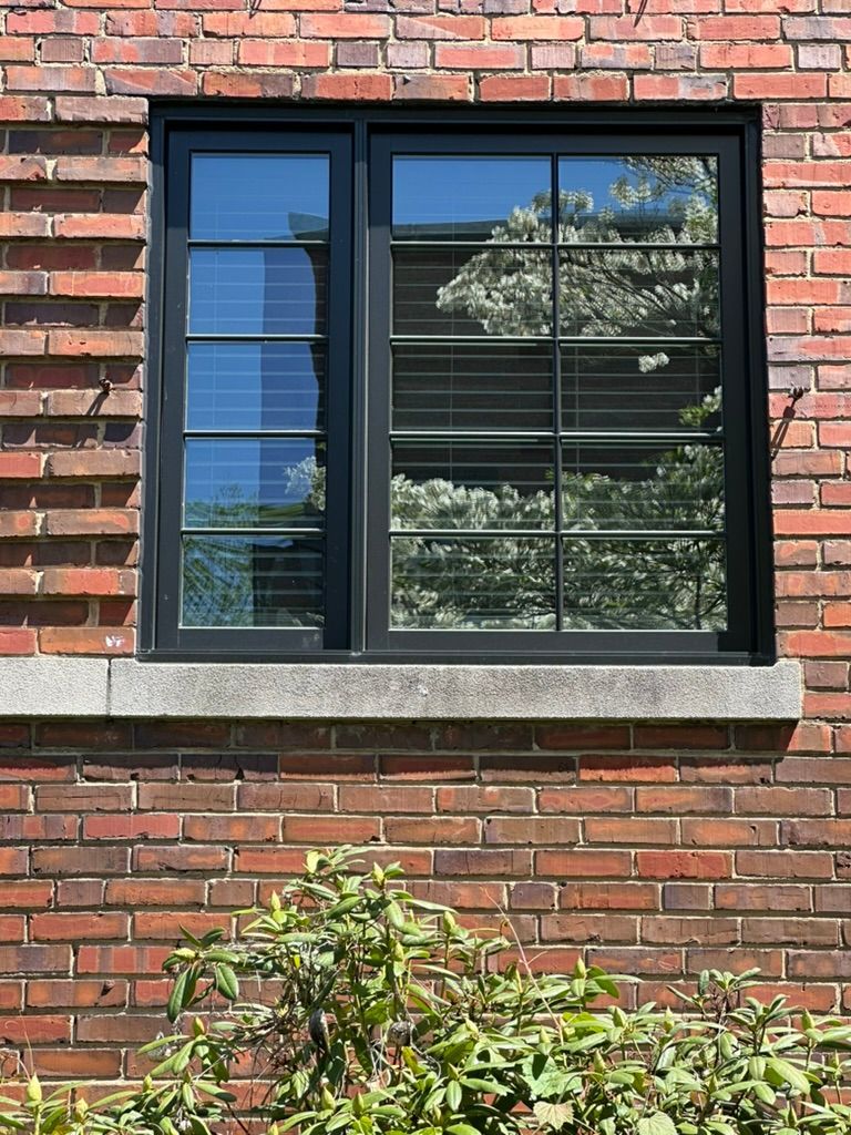 A black window is on a brick wall.
