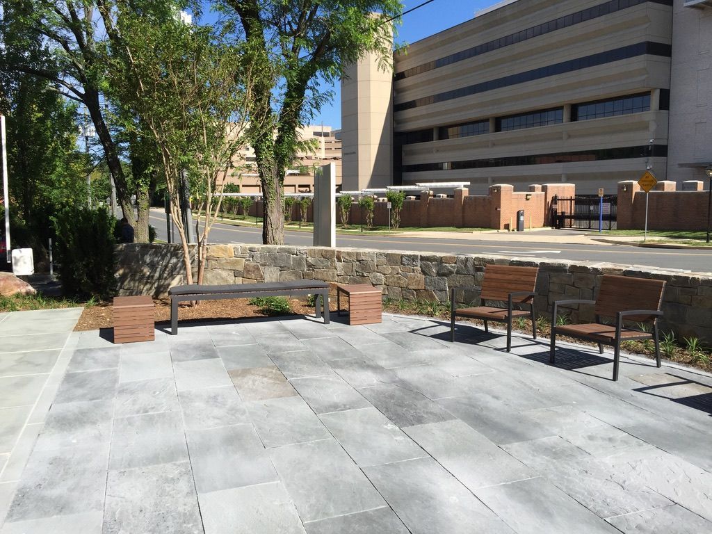 A group of benches are sitting on a sidewalk in front of a large building.