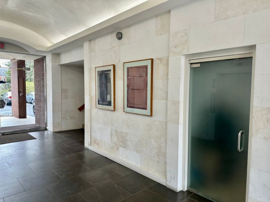 A hallway with a glass door and paintings on the wall